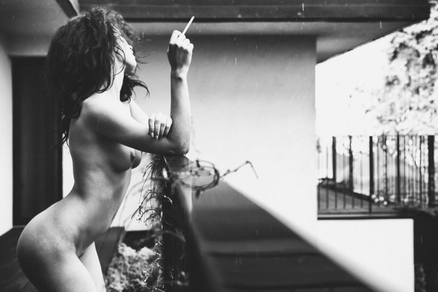 Голая женщина курит на балконе