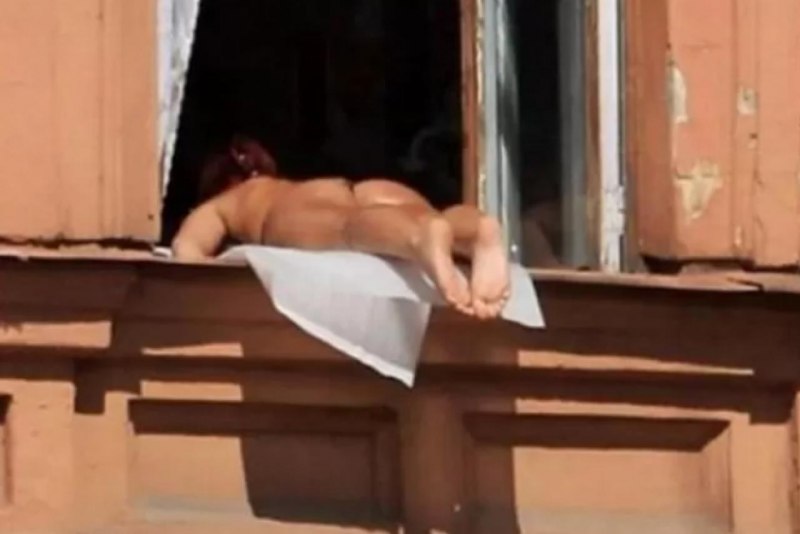 Девушка загорает в окне